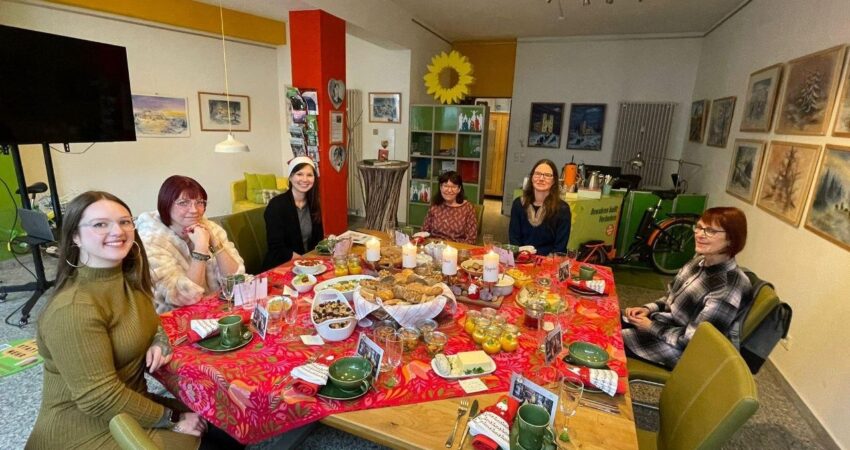 6 Frauen sitzen um einen weihnachtlich gedeckten Tisch