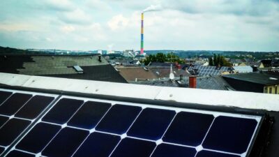 Solarpanels vor einem Stadtpanorama mit der bunten Esse der eins energie